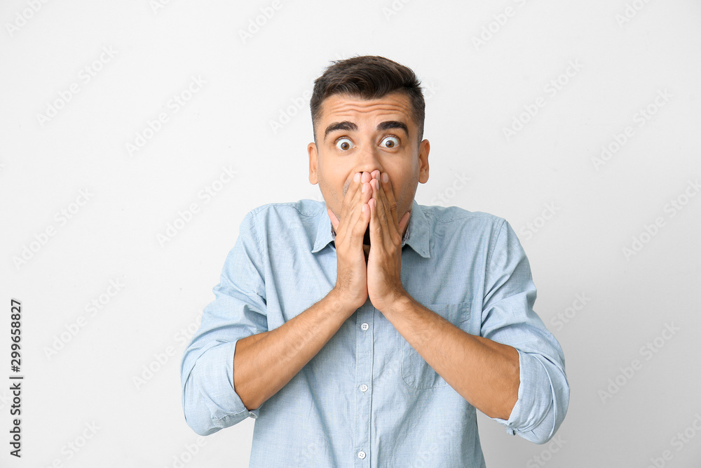 Shocked young man on light background