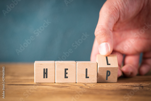 Fotografía hand is flipping a cube turning the word HELL into HELP on wooden background