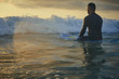 Male surfer getting ready for ride on the ocean wave against beautifull sinset light