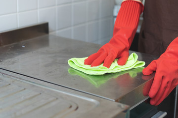 house maid cleaning sink in the kitchen with sponge and cleanser.
