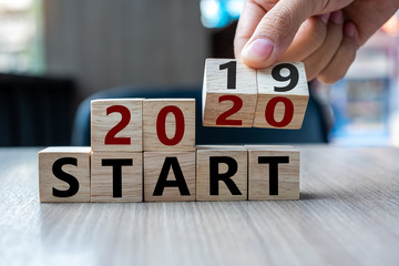 Business man hand holding wooden cube with flip over block 2019 to 2020 Start word on table background. Resolution, strategy, solution, goal, business and New Year holiday concepts