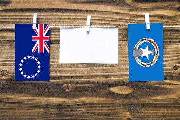 Wall Mural - Hanging flags of Cook Islands and Northern Mariana Islands attached to rope with clothes pins with copy space on white note paper on wooden background.Diplomatic relations between countries.