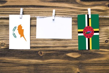 Hanging flags of Cyprus and Dominica attached to rope with clothes pins with copy space on white note paper on wooden background.Diplomatic relations between countries.