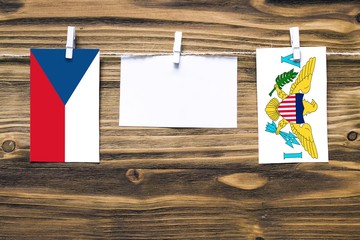 Hanging flags of Czech Republic and United States Virgin Islands attached to rope with clothes pins with copy space on white note paper on wooden background.Diplomatic relations between countries.