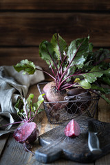 Fresh organic red beets with leaves in a wicker basket on a wooden table. Natural organic vegetables. Autumn harvest. Rustic