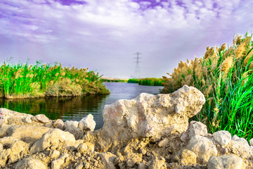 breathtaking view of a lake and clouds on the sky and heavy transmission electricity supply line in the background  