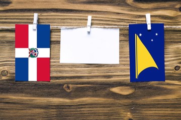 hanging flags of dominican republic and tokelau attached to rope with clothes pins with copy space o