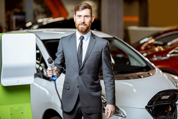 Salesman with electric car charging station in the dealership