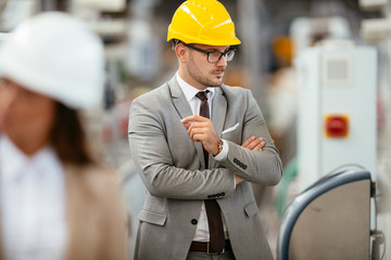 Businessman in warehouse. Young architect with helmet in suit. 