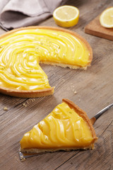 Wall Mural - lemon pie and slice on wood background