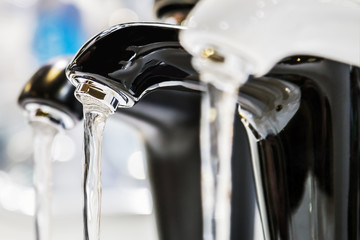 Wall Mural - taps with running water are on the shop window. The contrast of black and white