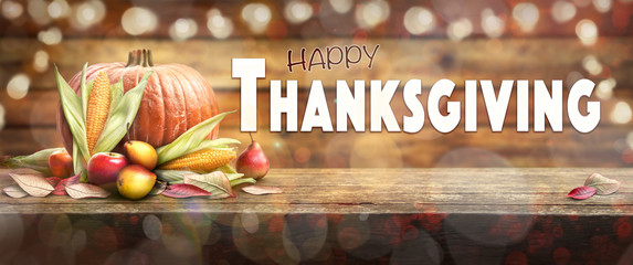 Thanksgiving celebration banner of pumpkins, apples, pears and corncobs on the left hand side of a table with a wooden background and the words. Happy Thanksgiving on the right.