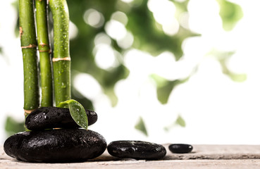 Grean bamboo leaves over zen stones pyramid on white background