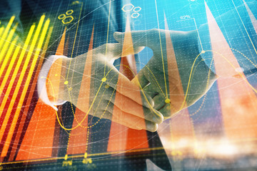 Double exposure of financial chart on cityscape background with two businessmen handshake. Concept of financial analysis and investment opportunities