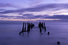 Beautiful Shot Of A Broken Bridge Over The Sea In The Fog Under A Purple Cloudy Sky