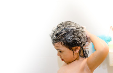 Little 4 years old asian girl in shower washing hair with shampoo.