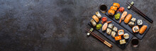 Sushi Rolls With Rice And Fish, Soy Sauce On A Dark Stone Background