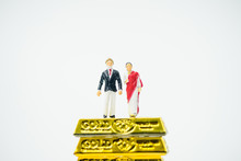 Miniature People :Senior Indian Couple And Rich People Stand On Pile Of Gold Bar On White Background.Concept For Money, Financial, Business Planning,Gold Business And Rich People In India.