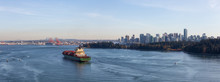 Vancouver, British Columbia, Canada. Aerial Panoramic View From Above Of A Cargo Ship Arriving To The Port With Downtown City In The Background During A Sunny Evening.