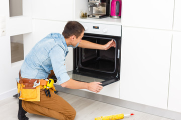 Wall Mural - Young Repairman Installing Induction Cooker In Kitchen