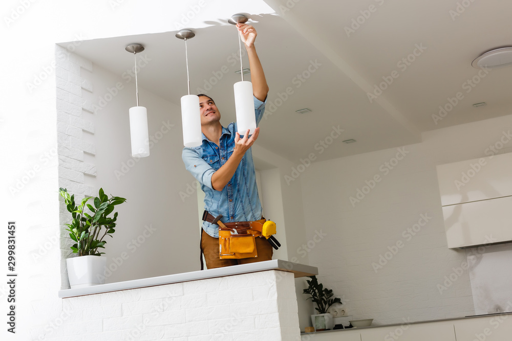 Electrician is installing and connecting a lamp to a ceiling. - obrazy, fototapety, plakaty 