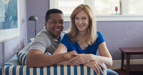 Fotografía Portrait of senior multi ethnic couple sitting on couch smiling at camera