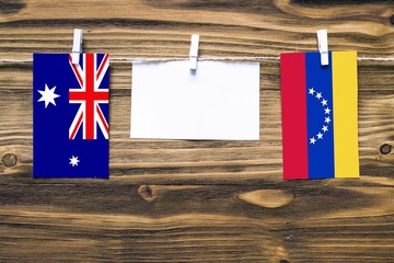 Canvas Print - Hanging flags of Heard and Mcdonald Islands and Venezuela attached to rope with clothes pins with copy space on white note paper on wooden background.Diplomatic relations between countries.