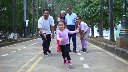 Poster - Slow motion of happy little girl running at the park while her family giving a support