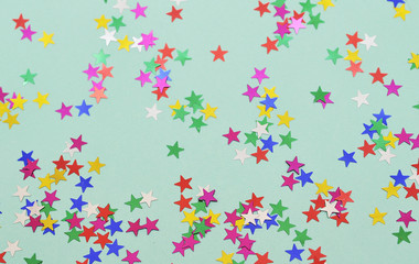 Wall Mural - Festive background. Colorful glitter stars on mint color background.