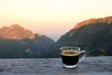Hot americano coffee on wooden table with mountain view
