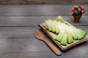 Wall Mural - melon sliced on dish with wooden forkon wooden table