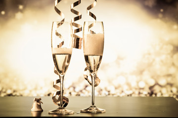 two champagne glasses with ribbons against holiday lights and fireworks - New Year celebrations