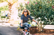 Cheerful young happy people enjoying the outdoor leisure activity riding a bike and smiling for happiness - young caucasian beautiful curly lady smile and enjoy the healthy ilfestyle