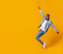 Funny Black Guy Posing On Tiptoes Over Yellow Background In Studio