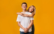 Young romantic couple embracing on yellow background