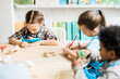 © pressmaster - Cute intercultural schoolkids sitting by table and drawing halloween symbols