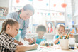 © pressmaster - Happy young teacher looking at Christmas drawing of little schoolgirl