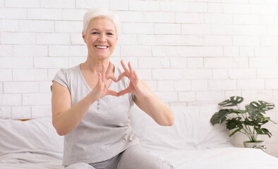 Cute senior woman making heart shape with her hands and fingers