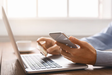 Unrecognizable businessman booking tickets online using smartphone and credit card.