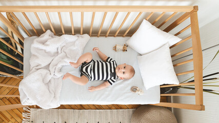 Curious newborn baby lying in crib and looking at camera