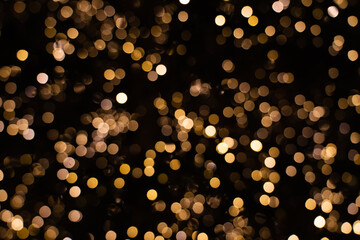blurry golden and white fairy string lights in dark night creating beautiful bokeh effect with glowi