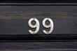 © nowyn - House number 99 on a black wooden front door