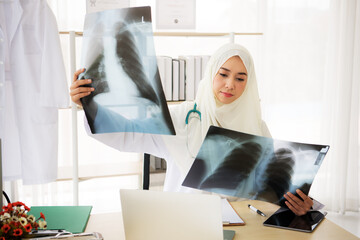 Wall Mural - Muslim woman medical doctor looking at x-rays result in a hospital