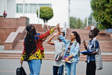 Wall Mural - Group of five african college students spending time together on campus at university yard. Black afro friends studying and gives high five each other.