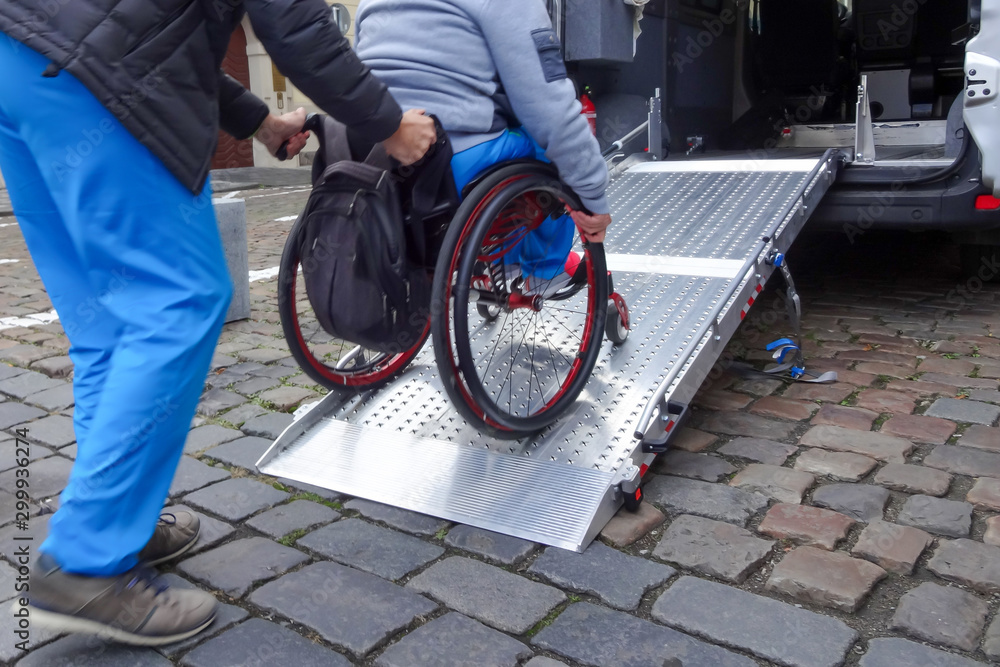 Assistant helping disabled person on wheelchair with transport using accessible van ramp - obrazy, fototapety, plakaty 