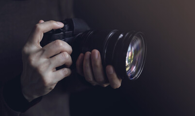 Young Photographer Woman using Camera to Taking Photo. Dark Tone. Selective Focus on Hand