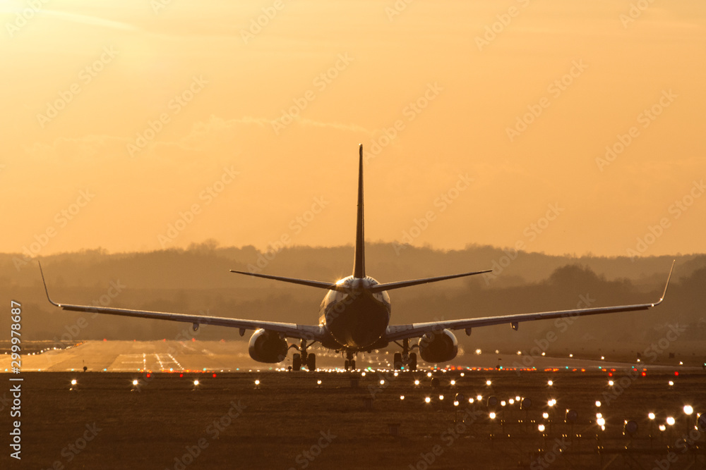 Lądowanie samolotu na lotnisku o zachodzie słońca - obrazy, fototapety, plakaty 