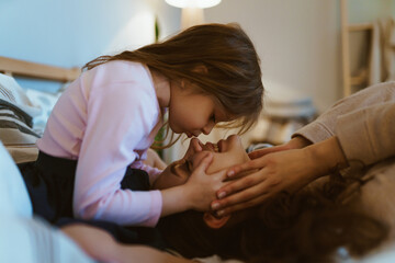 Wall Mural - daughter blows on her mom's nose in the bedroom