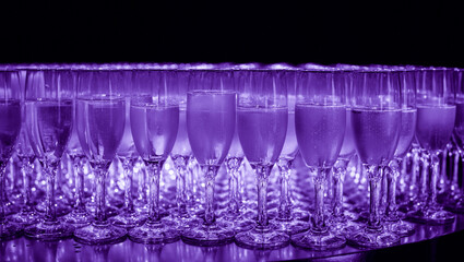 Elegant glasses with champagne standing in a row on serving table during party or celebration. Glasses background