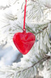 Read heart hanging on a snow-covered pine tree, vintage glass Christmas decoration